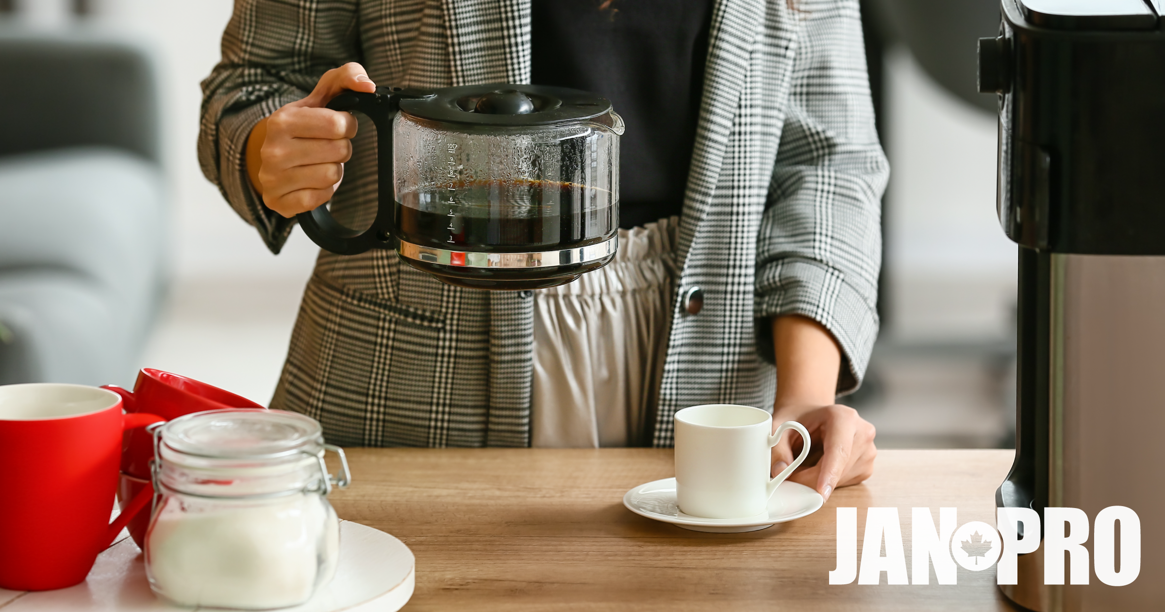 An individual holding a coffee pot in a breakroom